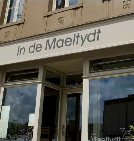 De gevel met het grote uithangbord "In de Maeltydt" boven de ramen van de zaak