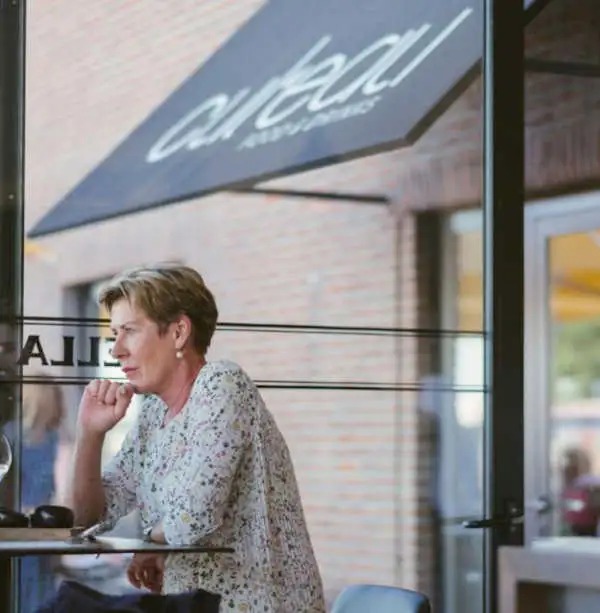 Zicht door het raam op een gast aan tafel, met de luifel met het cul’eau-logo in het glas