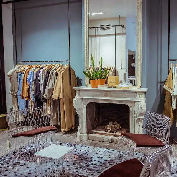 Winkelinterieur met een rek jassen naast een witte marmeren schouw met spiegel
