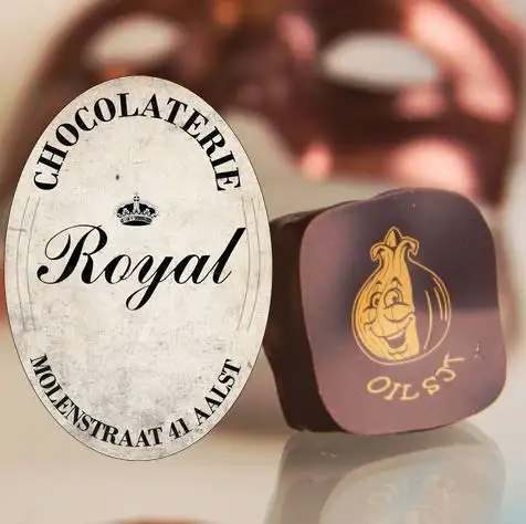 Praline met het gouden Oilsjterse ajuinfiguurtje naast het ovale logo van Chocolaterie Royal